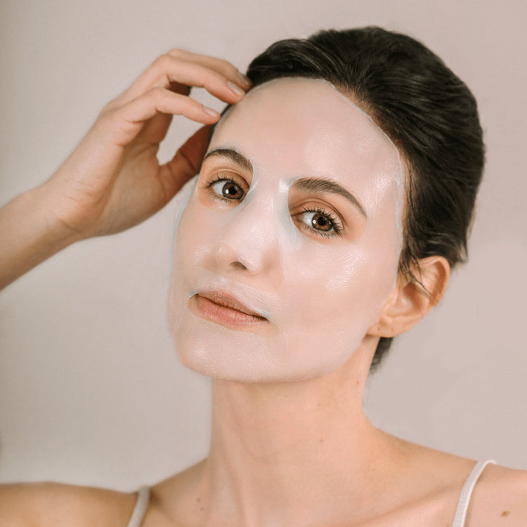 A woman applying a Hadaka 24KT Gold Facial Mask